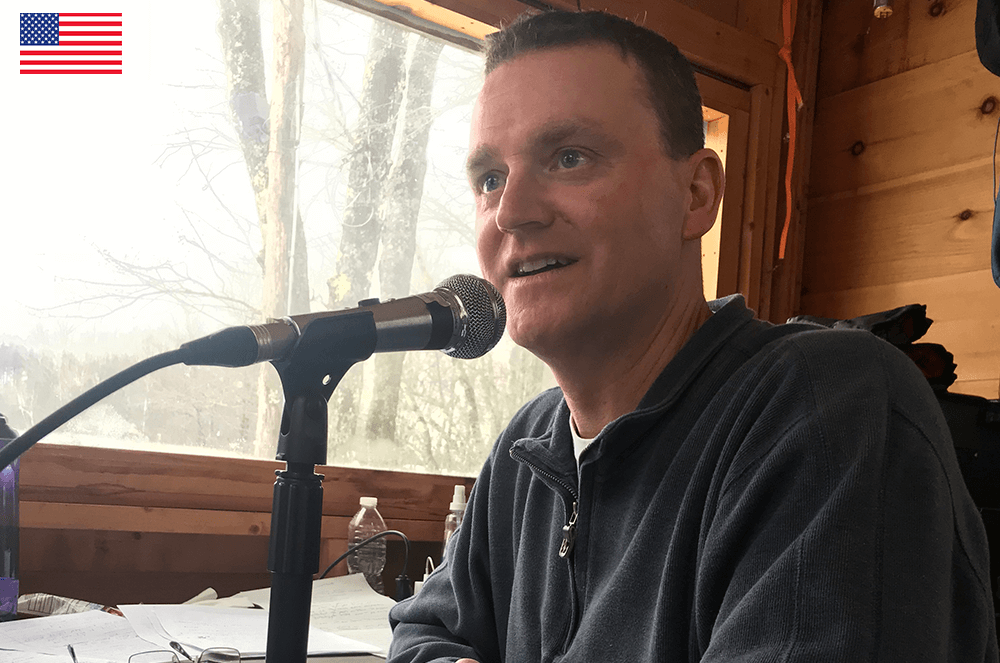 Man speaking into microphone at desk