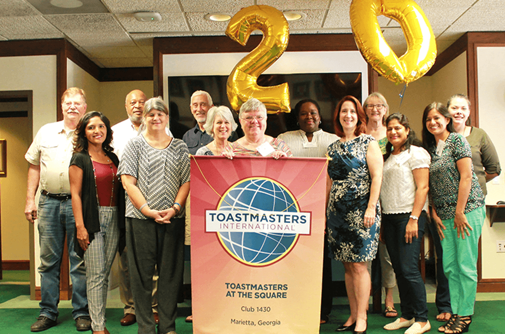 Group of people posing with banner and balloons