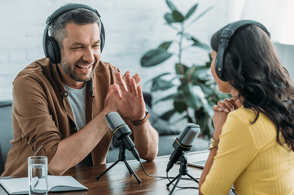 Man and woman speaking with headphones and mics