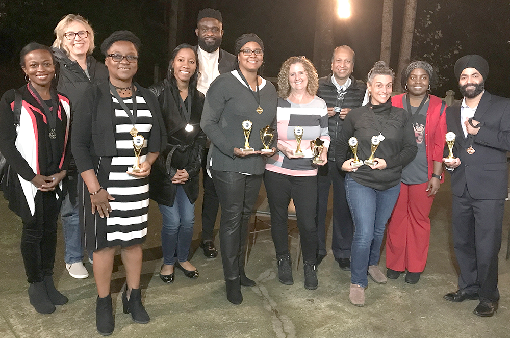 Group posing outdoors with awards